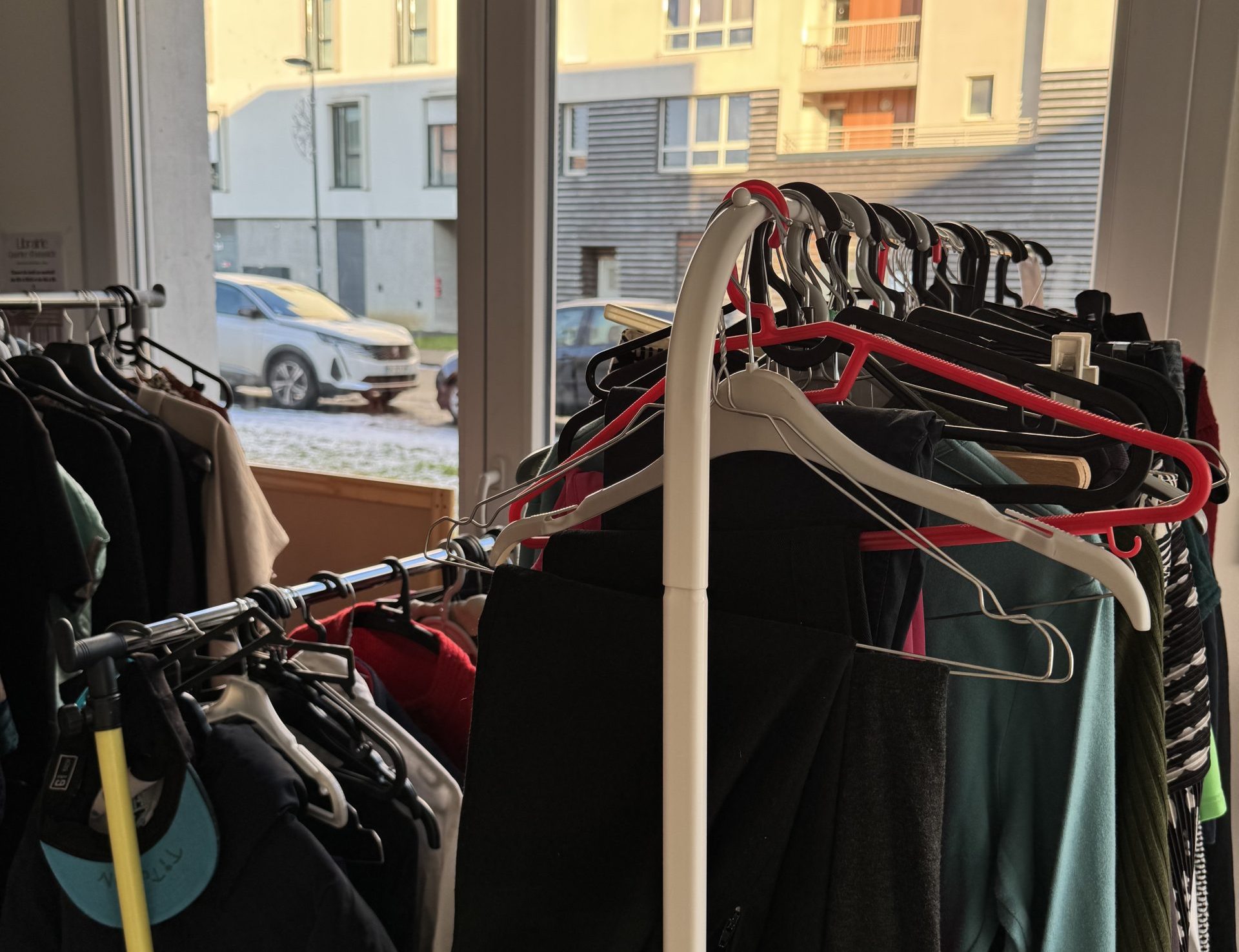 Photo des portants avec des vêtements dans le vestiaire solidaire de la Maison des Projets